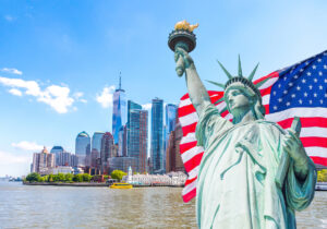 statue of liberty with a large american flag and new york skyline in the background